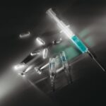 Vials and pills next to a syringe.