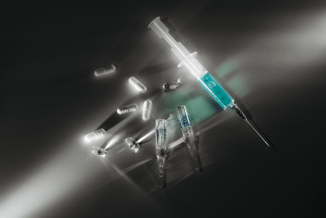 Vials and pills next to a syringe.