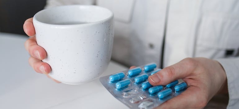 Doctor holding a glass of water and a blister of pills.