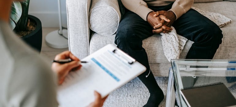 Woman writing in a clipboard while talking about genetics and addiction with her client.