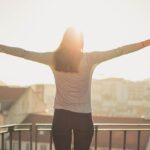 Woman spreading her arms while looking at the sun.
