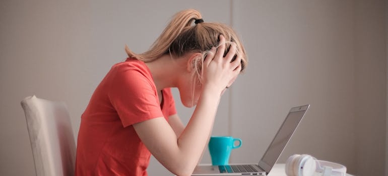 Woman stressing herself while looking at a laptop.