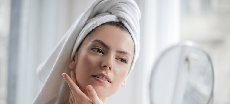 Woman looking at her clear skin, one of the common benefits of sobriety.