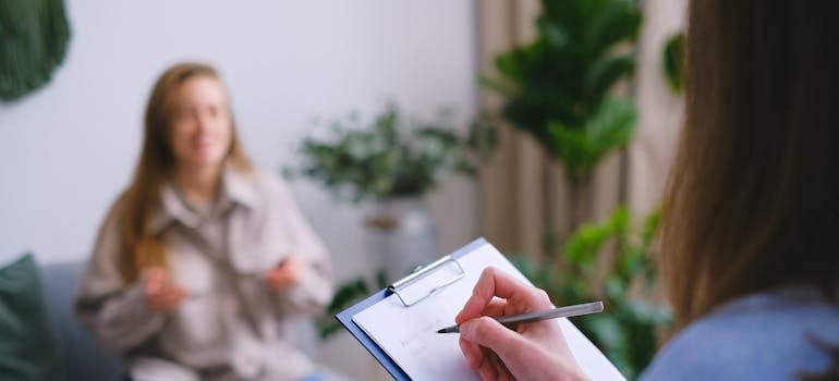 Psychologist writing in a clipboard while talking to a patient about transfer addiction.
