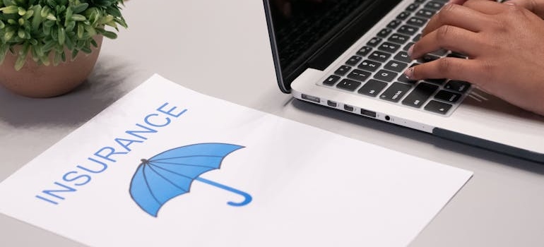 Insurance document next to a laptop.