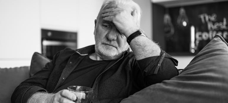 Older man suffering with alcoholism thinking about senior addiction treatment.