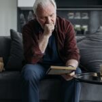 Older man drinking whiskey while suffering with grief and substance abuse.