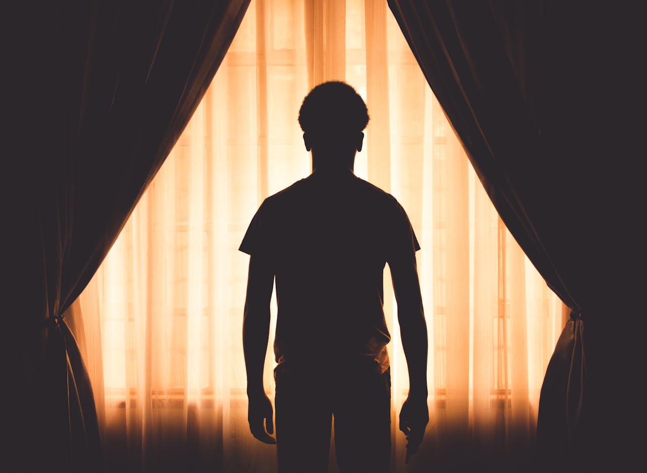 Man looking out the window while going through the stages of relapse.
