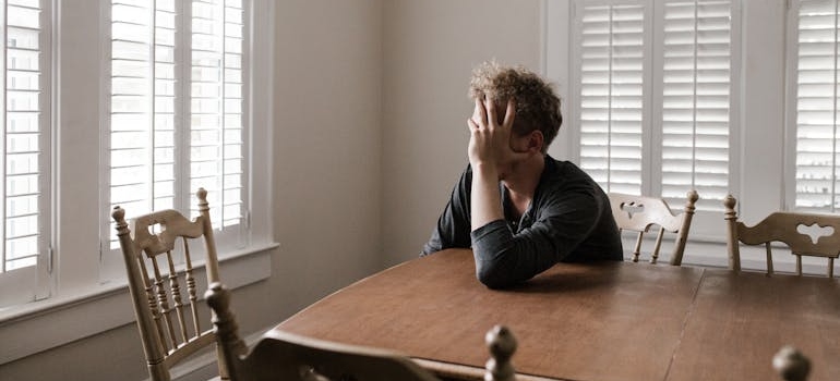 Man sitting at a table while struggling with seasonal affective disorder and addiction.