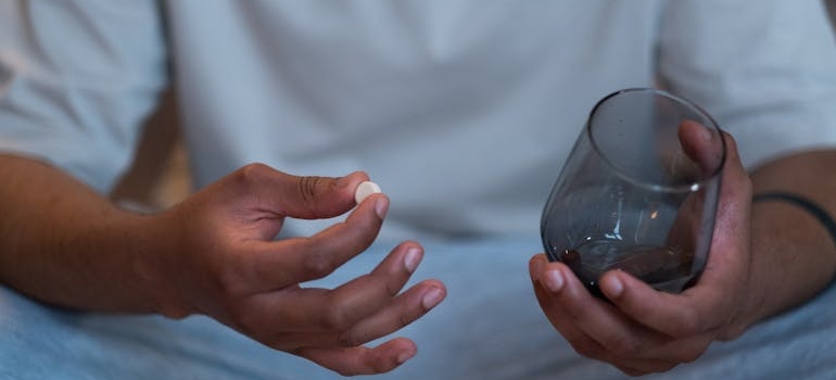 Man holding a pill and a glass of water.