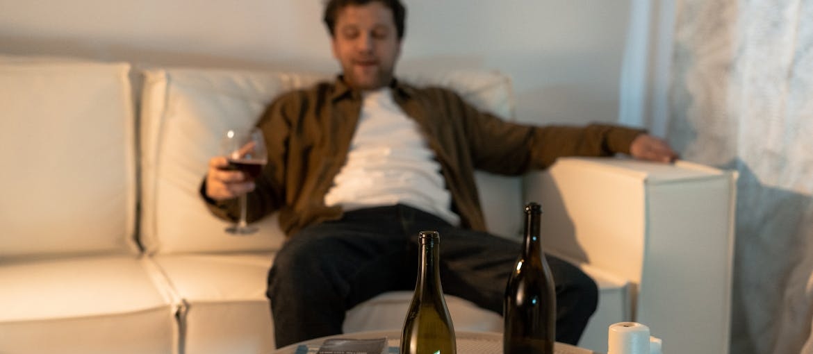 Man sitting on the couch and drinking a glass of wine.