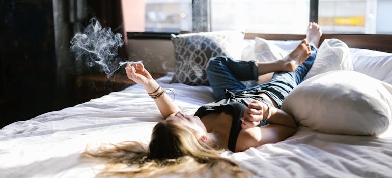 Woman lying in bed and smoking weed.