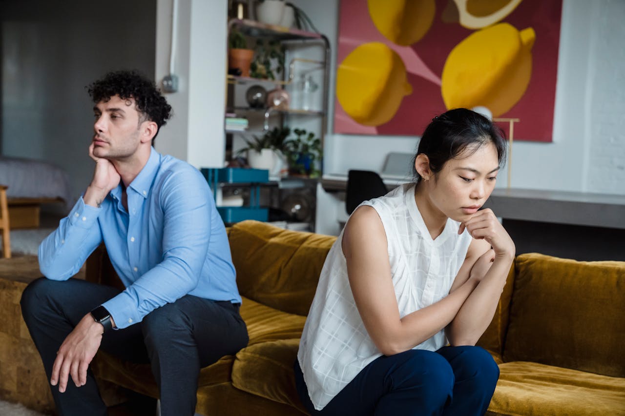 Couple in a codependent relationship sitting on the couch angry at each other.