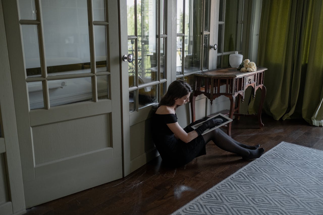 Woman sitting on the floor, looking at a picture while coping with loss.
