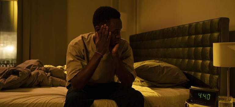 Man with insomnia looking at the clock on his bedside table.