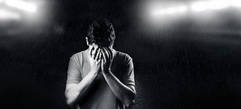 Scared man covering his face while struggling with LSD and bipolar disorder.