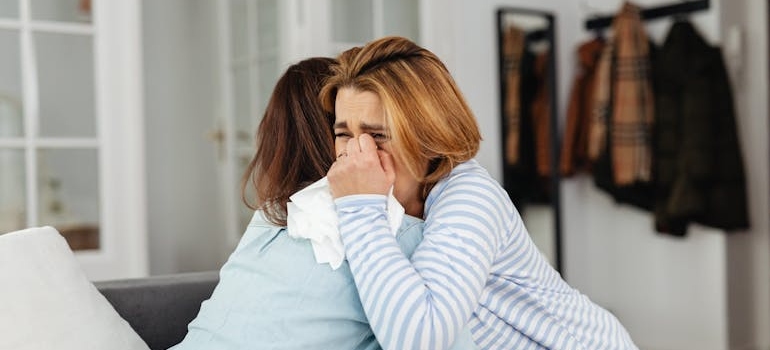 Woman crying and hugging her friend while coping with loss.