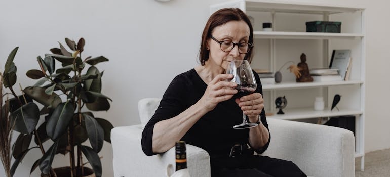 Woman drinking a glass of wine while coping with loss.
