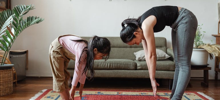 Woman stretching in the living room with her daughter.
