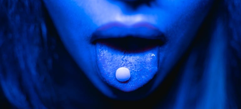 Woman putting a pill on her tongue.