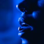 Woman with a pill on her tongue wonder what drugs are in ecstasy.