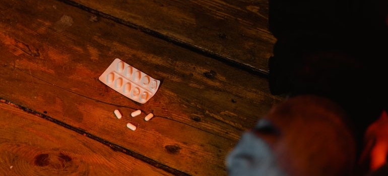 White medication tablets scattered beside an empty blister pack on a wooden surface.