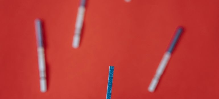 Person holding a pregnancy test strip against a red background.