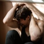 Scared man covering his face while struggling with LSD and bipolar disorder.