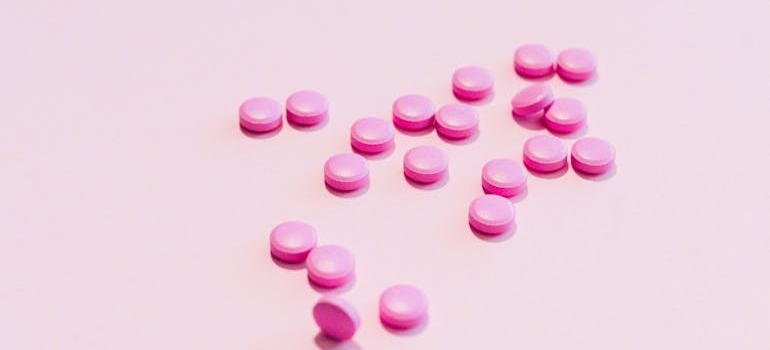 Small, pink pills on a pink background.