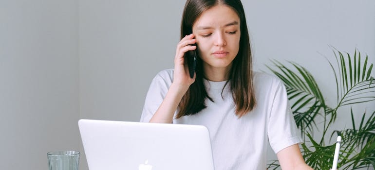 Woman making a phone call while writing in a notebook.