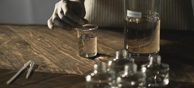 Person wearing gloves stirring a sample in the water.