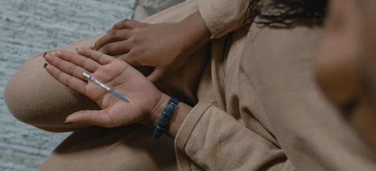 Close-up of a person holding a small medical testing strip with visible result lines.