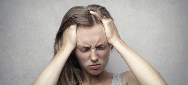 Woman having a headache, one of the signs and symptoms of Adderall abuse.