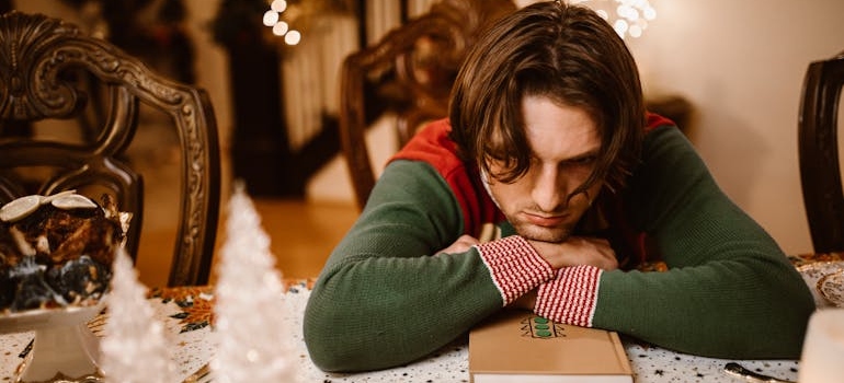 Man sitting a table while suffering with Christmas depression.