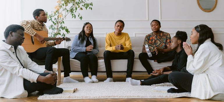 People sitting in a living room and singing and playing instruments.