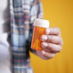 Man holding an orange prescription bottle.