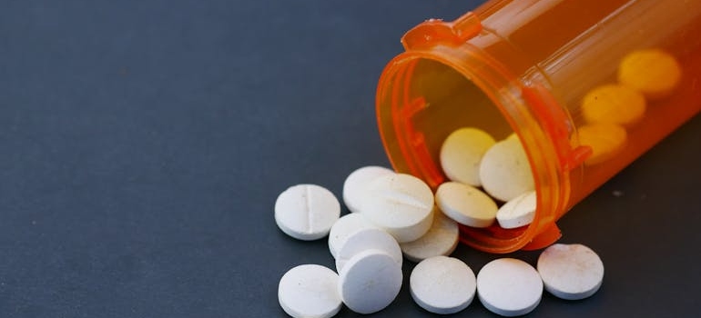 White pills spilling out of an orange prescription bottle.