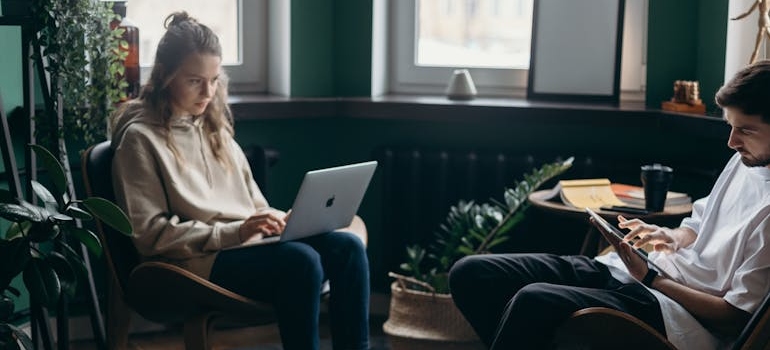 Woman working on her laptop and man working on his tablet.