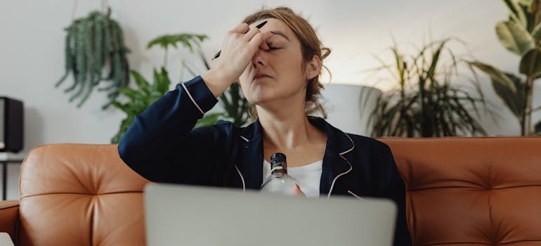 Woman holding a bottle of alcohol while struggling with the latter stages of alcoholism.