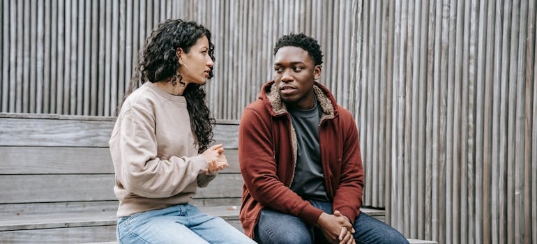 Two people sitting on the bench and having a serious conversation.