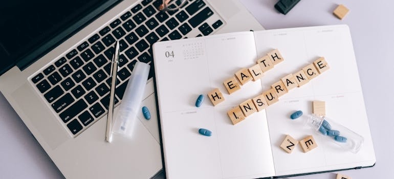 Health insurance spelled with letter blocks on top of a notebook.