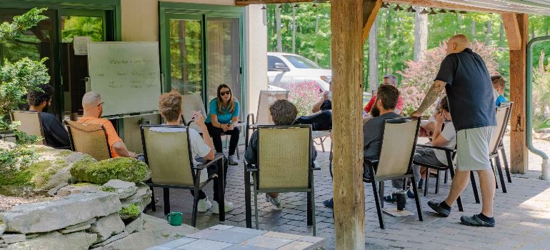 a therapist with patients sitting around her outside of Little Creek Lodge during addiction treatment program