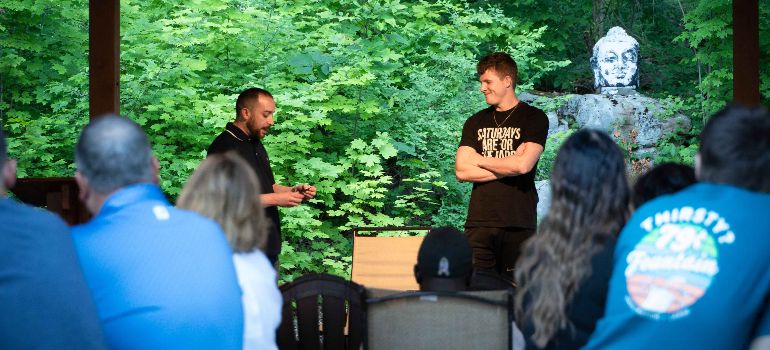 A therapist and young man talking on a podium in front of other patients