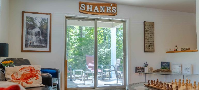 an interior view of Shane's House featuring a couch, chess table and sliding door
