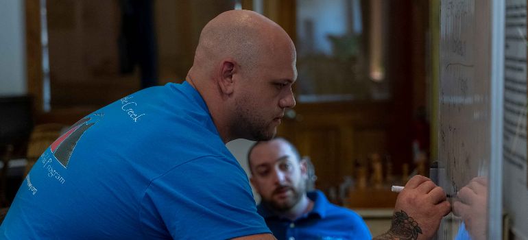 Two Little Creek therapists in front of the white board, while one of them is writing on it