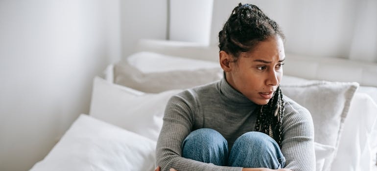 Worried woman sitting on the bed thinking about self-medication for bipolar disorder with substances.