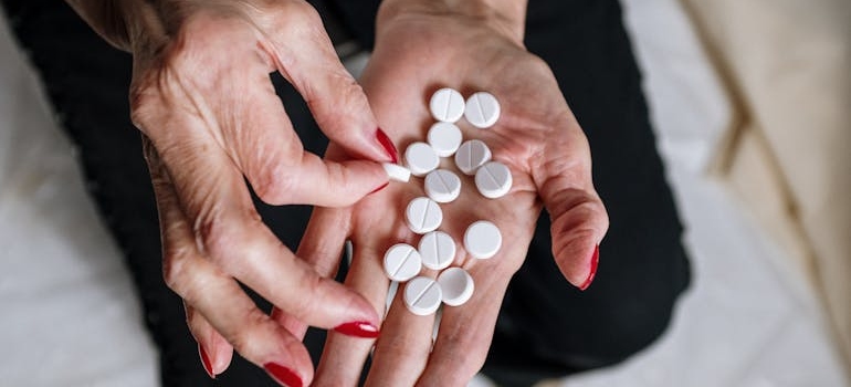 Woman counting white pills on her hand.