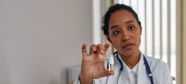 Woman holding a vial of medication while talking to a patient.