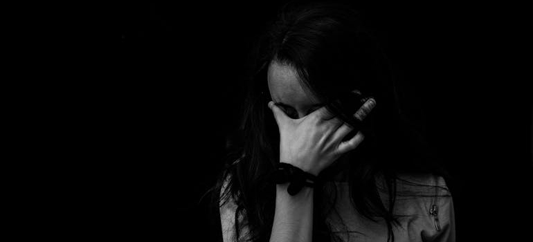 Black and white picture of a woman covering her face with her hands.