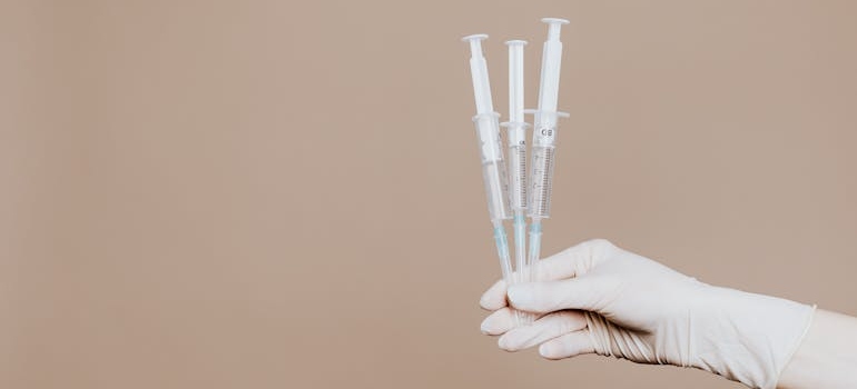 Nurse holding three syringes.